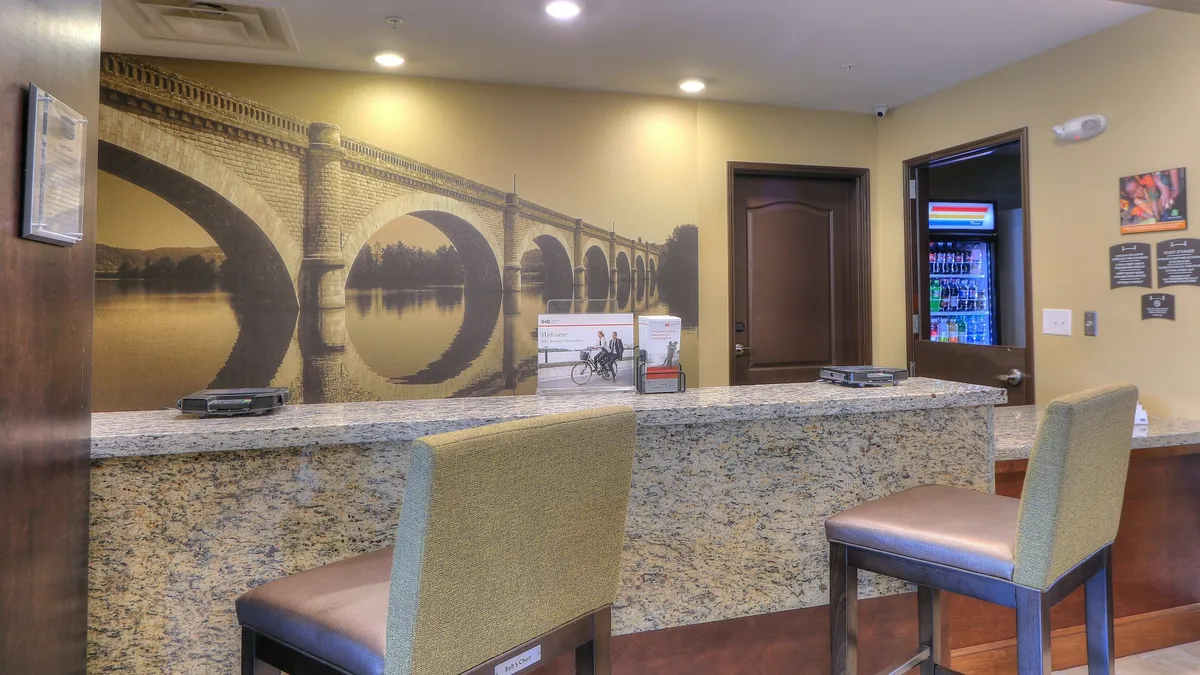 A welcoming reception area featuring a granite countertop, a mural depicting a bridge, and comfortable seating. The area radiates an inviting, professional atmosphere, making it suitable for families to gather and for guests to get information about the property or local attractions.